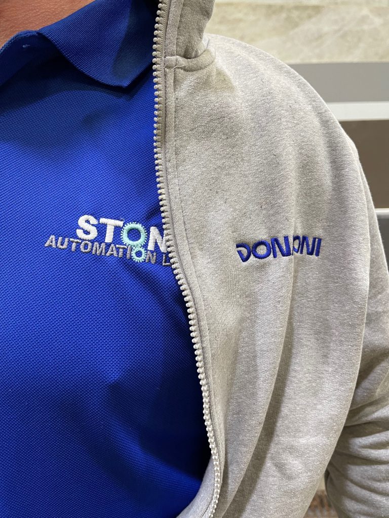 A close up picture of one of the team's chest showing their Stone Automation branded t-shirt and Donatoni jacket